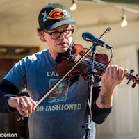 a man in glasses playing a violin in front of a microphone