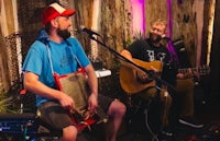 two men playing instruments in front of a microphone